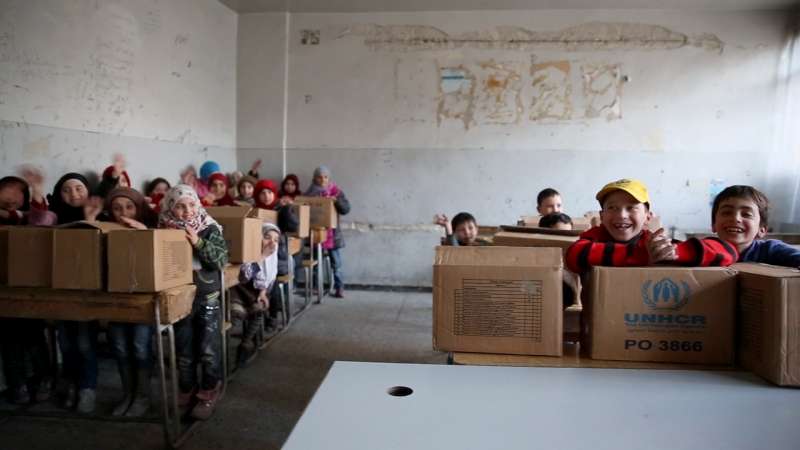 Crianças em escola no leste de Alepo recebem caixas com roupas de inverno. O ACNUR conseguiu distribuir ajuda humanitária durante o cessar-fogo temporário na região. Foto: ACNUR