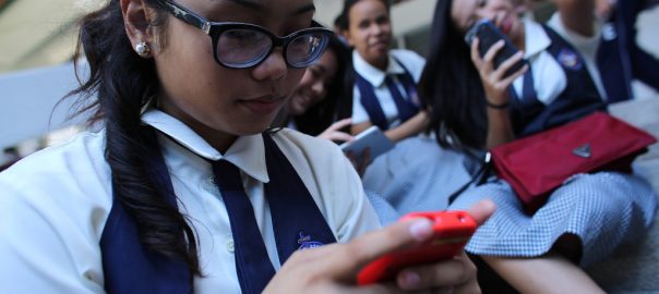 Estudantes mexem no celular durante recreio em escola de Cebu, nas Filipinas. Foto: UNICEF/Estey